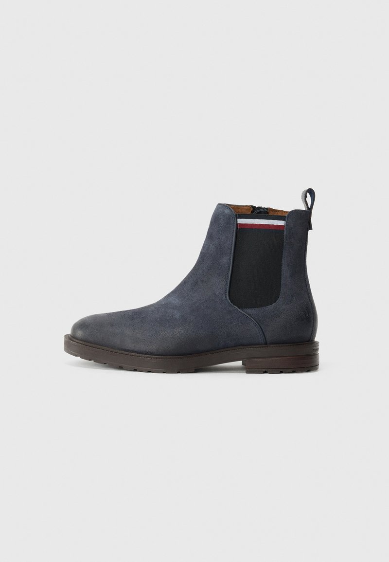 Marinblå mocka Chelsea-boots med elastiska sidopaneler, en dragflik och en brun gummisula. Texturerad finish och minimalistisk design.