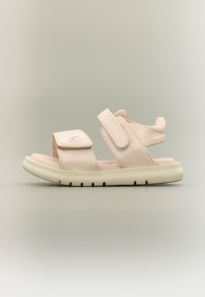 Lichtroze sandaal met twee verstelbare klittenbandsluitingen en een gedempte zool op een neutrale achtergrond, zijaanzicht.