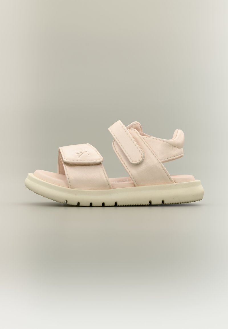 Ροζ ανοιχτόχρωμο σανδάλι με δύο ρυθμιζόμενους ιμάντες βέλκρο και επένδυση σόλας σε ουδέτερο φόντο, απεικονιζόμενο από το πλάι.