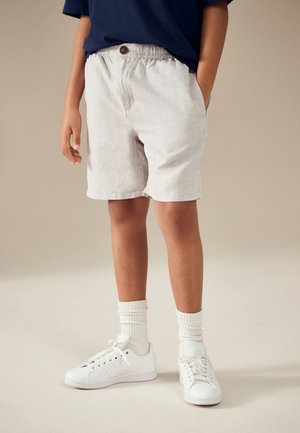 Lysegrå linned-shorts med elastisk talje og knappedetalje, kombineret med hvide sneakers og hvide ribstrikkede crew-sokker.