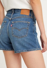 Shorts in denim di colore azzurro chiaro con vita alta, una patch in pelle del marchio e due tasche posteriori con cuciture a contrasto.