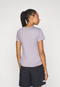 Short-sleeve, lilac t-shirt made of lightweight fabric. The design includes a rounded neck and slight curvature at the hem. Worn with black shorts.