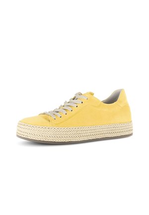 Gele suède sneaker met dikke gevlochten plateauzool en grijze veters, zijaanzicht op witte achtergrond.