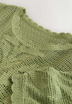 Light green knitted fabric with open weave and scalloped edges, shown in close-up with soft folds.