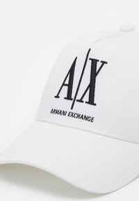 Cappello bianco con logo ricamato nero "A/X" e testo "ARMANI EXCHANGE". Realizzato in tessuto liscio, con visiera strutturata e cinturino regolabile.