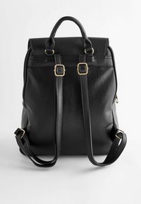 Sac à dos en cuir noir avec poignée supérieure, bretelles réglables, accents de boucle dorée et fermeture éclair sur fond blanc uni.