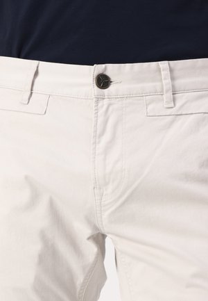 Pantalones de algodón color crema con cierre de botón, bolsillos estándar y detalles de costura sutiles. Textura suave con corte recto.