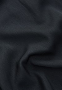 Tissu noir lisse avec des plis doux et une texture subtile, éclairé uniformément pour montrer les détails fins de la surface du matériau.