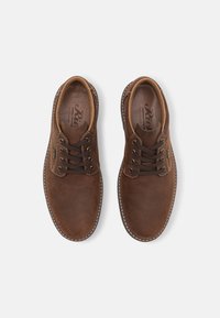 Scarpe in pelle marrone con punta tonda, soletta texturizzata e lacci marrone scuro. Cuciture a contrasto lungo i bordi e logo del marchio visibile all'interno.