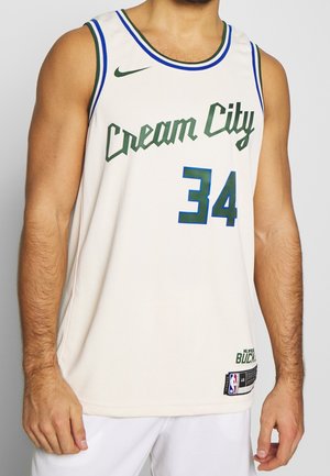 Valkoinen koripallopaita, jossa on teksti "Cream City", numero 34 ja Milwaukee Bucksin logo, jonka päällä näkyy näkyvät kädet ja vartalo.