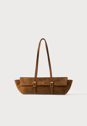Brown crocodile-texture leather handbag with two front buckle straps and long shoulder handles on a plain background.