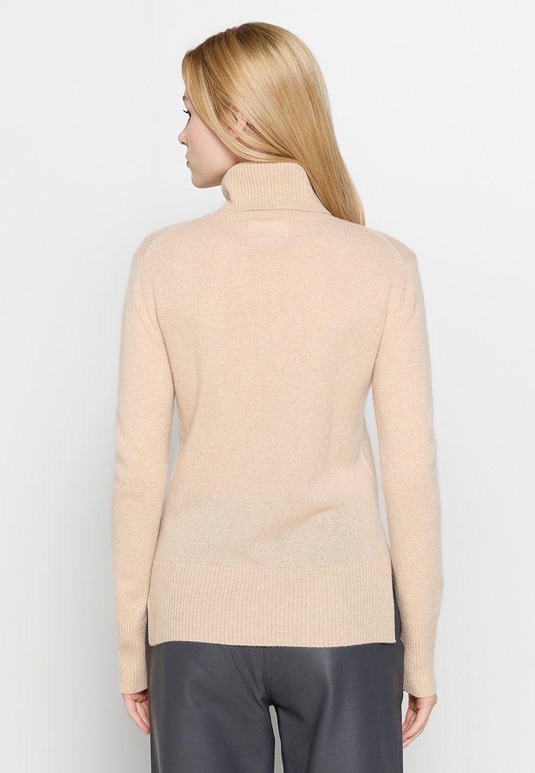 Beżowy sweter wykonany z miękkiego materiału, z wysokim kołnierzem, długimi rękawami i ściągaczem na dole. Gładka tekstura, prosty design.