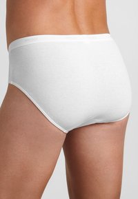 Slip in cotone bianco con una texture liscia e un taglio classico, caratterizzato da un morbido elastico in vita impresso con il nome del brand.