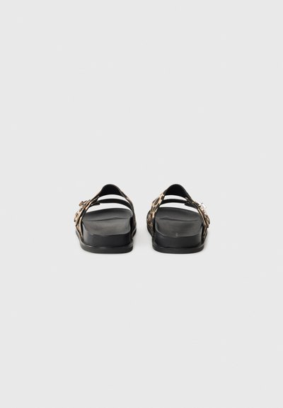 Schwarze Slidesandalen mit Leopardenmuster-Riemen, die mit einer verstellbaren Schnalle und einer glatten, flachen Gummisohle ausgestattet sind.