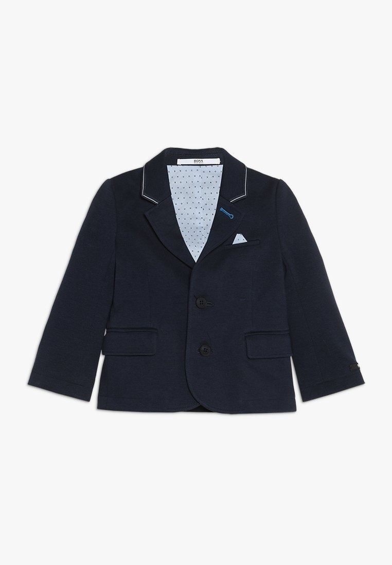 Granatowa marynarka na dwa guziki, z wyłogami z wycięciem, przednimi kieszeniami oraz jasnoniebieską podszewką w kropki. Na klapach znajdują się białe przeszycia jako akcenty.