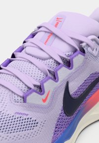 Heledad helesinet tumeroosa värviga, millel on võrgust pealispind, kontrastse tumeda sinise logoga ja kirjude aksessuaaridega tallal ja silmade ümber.