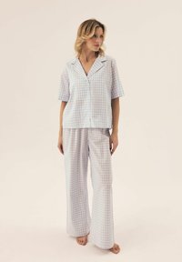 Jasnoniebieski i biały zestaw piżamowy w kratkę, składający się z krótkiego rękawa z guzikami i szerokich spodni, wykonany z miękkiego materiału.