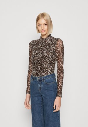 Haut à manches longues en tissu transparent à imprimé léopard, avec un col montant et une coupe ajustée, associé à un pantalon en denim taille haute.