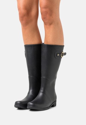 Černé gumové kozačky po kolena s texturovaným povrchem, zdobené zlatou sponou a plochou podrážkou pro stabilitu.