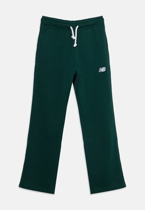 Pantalon de survêtement vert foncé avec cordon blanc et petit logo New Balance sur la cuisse gauche, posé à plat sur fond blanc.