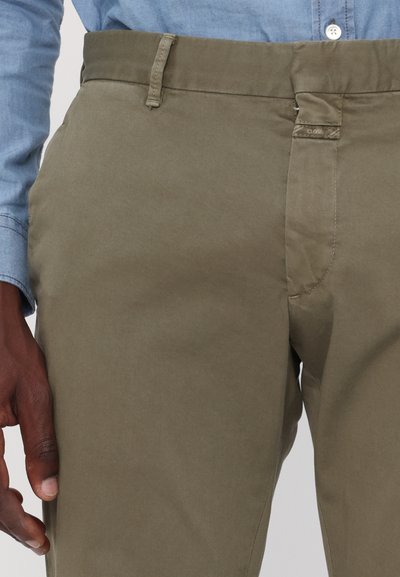 Chinos vert olive en tissu mélangé de coton, avec une taille standard, des poches latérales et une texture lisse.