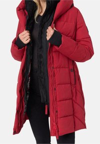 Red puffer coat with a textured, quilted design, featuring a black inner lining, hood, and zippered front with button accents.