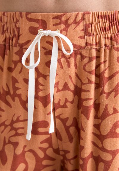 Shorts en coton marron avec un motif abstrait corail, taille élastique avec un cordon blanc, et œillets en ton doré.
