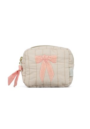 Pequeño bolso acolchado beige con un lazo rosa bordado en el frente y una etiqueta de tela rosa para tirar de la cremallera en el lado izquierdo.