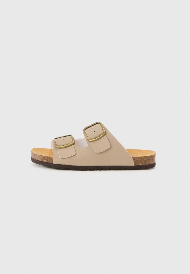 Sandales beiges avec deux boucles métalliques, un semelle en liège moulée et une semelle en caoutchouc. Design minimaliste et profil plat.