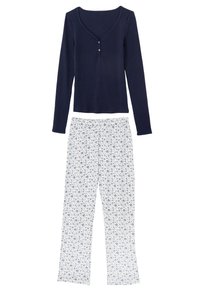 Marinblå långärmad topp med rund halsringning och knappdetalj, kombinerad med vita byxor med blått blomstertryck. Tyg i bomullsblandning.