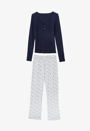 Marineblauw top met lange mouwen, een ronde halslijn en een knoopdetail, gecombineerd met witte broek met een blauw bloemenpatroon. Gemaakt van een katoenmix.