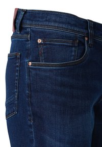 Dunkelblaue Denim-Jeans mit einem klassischen geraden Schnitt. Merkmale sind Kupferriegel, ein rot gesticktes Detail und mehrere Taschen.
