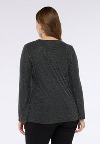 Czarna bluzka z długim rękawem z pionowymi srebrnymi paskami, okrągłym dekoltem i gładką fakturą, z lekko zakrzywionym szwem z tyłu.