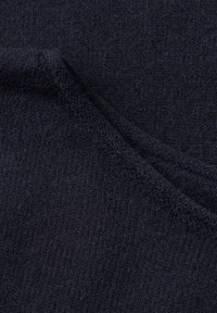 Tissu bleu marine foncé avec un tricot doux et texturé et un pli visible créant une ligne diagonale à travers le matériau.