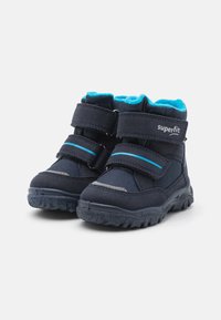 Baskets montantes bleu marine avec deux bandes Velcro, présentant une doublure douce turquoise, une semelle en caoutchouc texturée et des accents réfléchissants.