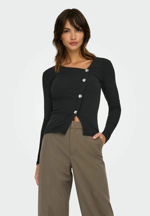 Haut long à manches noires côtelées avec un décolleté carré, présentant quatre boutons brillants sur une patte oblique et un détail de nœud à l'avant.