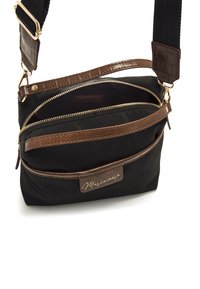 Borsa in nylon nera con dettagli in finta pelle marrone, due scomparti con zip, tracolla regolabile e una patch con logo sul davanti.