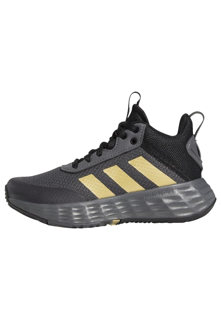 Black and gray athletic shoe with yellow three-striped logo, breathable mesh upper, padded collar, and textured rubber sole.