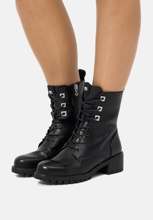 Stivali alla caviglia in pelle nera con design a lacci, dettagli metallici, zip laterale e suola texturizzata con tacco spesso.