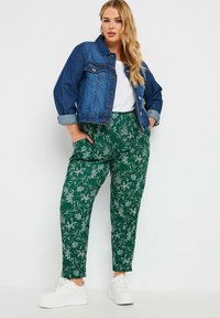 Denimjacka med långa ärmar, krage och framfickor. Grönblommiga byxor med elastisk midja och sidofickor. Vita sneakers.