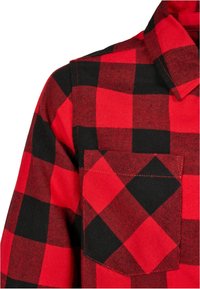 Rød og sort ternet flannel-skjorte, der viser krave, skulder, ærme og en brystlomme.