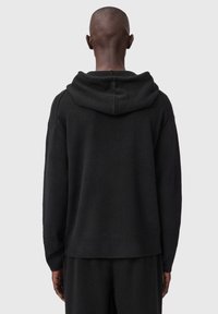 Zwarte hoodie gemaakt van zacht materiaal. Heeft een losse pasvorm, geribbelde manchetten en een subtiel textuurpatroon op de stof.