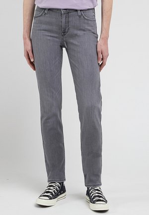 Jeans de mezclilla gris con un corte ajustado, que cuentan con cinco bolsillos y costuras en contraste, combinados con zapatillas negras de caña alta.