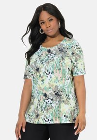 Tričkové s krátkým rukávem a kulatým výstřihem vyrobené z lehkého materiálu, s zeleným květinovým potiskem a černými a béžovými akcenty.