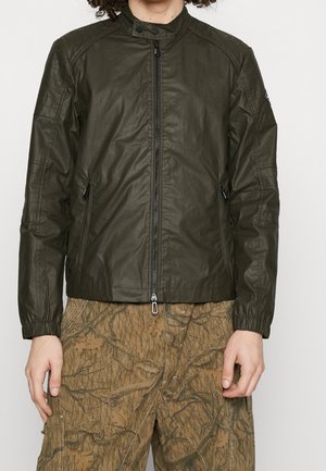 Giacca leggera verde oliva con colletto alto, zip frontale e due tasche laterali; presenta polsini elasticizzati e cuciture dettagliate.