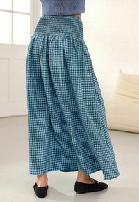 Jupe maxi à carreaux bleus et noirs avec une taille smockée et un tissu fluide, présentant une silhouette décontractée et une coupe longueur cheville.