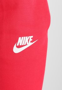 Närbild av röd tyg med vit Nike-logotyp tryckt på ytan.