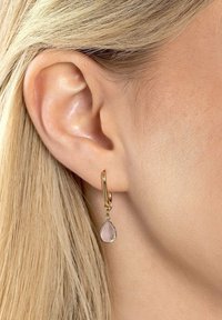 Orecchino a cerchio dorato con una pietra preziosa rosa a forma di goccia appesa, caratterizzato da una superficie liscia e una finitura lucida.