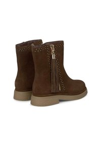 Bottines en daim marron avec une finition texturée, présentant des clous décoratifs, un accent de frange et une fermeture éclair sur le côté pour un enfilage facile.