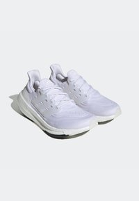 Witte sportschoenen met een bovenwerk van mesh, een gestructureerd ontwerp en verstevigde middenzolen. Heldere accenten en een zwarte rubberen buitenzool.